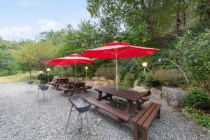 a group of picnic tables with red umbrellas at Sokcho White Lighthouse Pension in Sokcho