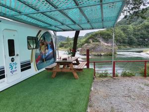 un tavolo da picnic sotto un tendone accanto a un fiume di Youngwol Dongkang Village Caravan a Yeongwol