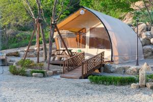 a tent with a wooden staircase and a wooden porch at Inje Naerincheon Glamping in Inje