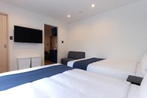 une chambre d'hôtel avec deux lits et une télévision à écran plat dans l'établissement Hotel SALIFORT HAKATA, à Fukuoka