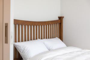 a bed with white sheets and a wooden headboard at Gangneung Stay 302 in Hwapyeong-dong