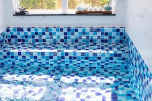 a blue tiled tub in a bathroom with a window at Gangneung Stay 302 in Hwapyeong-dong +34 photos