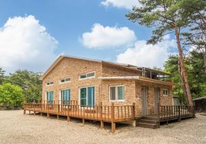a brick house with a large wooden deck at Baekdam Gyegok Pension in Inje