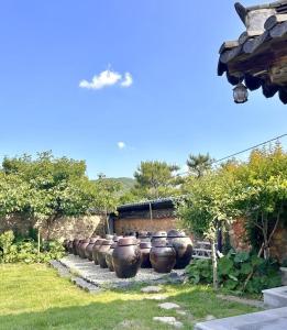 a row of large pots lined up in a yard at Sanencheong Namsayedamchon Yedam Hanok Stay in Sancheong +7 photos