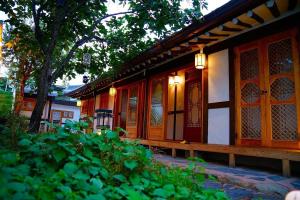 a building with red doors and windows and trees at Jeonju Hongsi Hanok Guesthouse in Jeonju