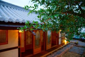 a building with a tree in front of it at Jeonju Hongsi Hanok Guesthouse in Jeonju