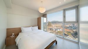 a bedroom with a large bed and a large window at Taean Oaten Pool Villa in Taean