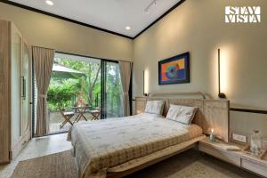 a bedroom with a bed and a balcony with a table at StayVista at Parkville Apartment in Alibaug