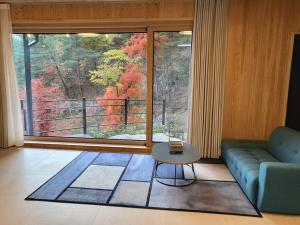 a living room with a couch and a table and a large window at Daon Forest Pension in Inje