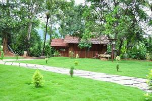 un jardin avec une maison en arrière-plan dans l'établissement Vattakkuny Wild Orchid Resorts, à Thirunelli