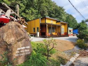 a yellow building with a sign on a rock at Deokdong Dalguji Pension in Jecheon