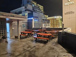 a group of wooden picnic tables in a city at night at Forest Pension in Busan
