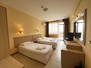 a hotel room with two beds and a television at Александра in Sveti Vlas