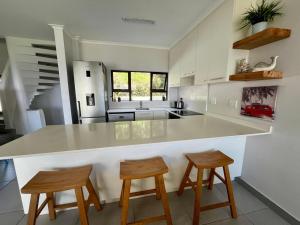 a kitchen with a white counter and two stools at The Umdloti Lighthouse Tripelx in Umdloti