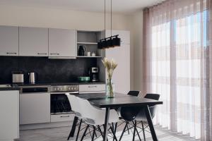 a kitchen with a dining table and white cabinets at Apartment C8 mit Balkon & Nutzung der Wellness- & Aktivbereiche im "Pine Hill Resort" in Zirchow