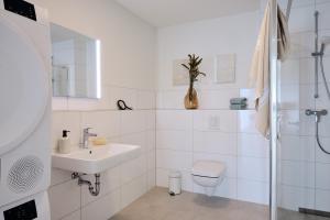 a white bathroom with a sink and a toilet at Apartment C8 mit Balkon & Nutzung der Wellness- & Aktivbereiche im "Pine Hill Resort" in Zirchow