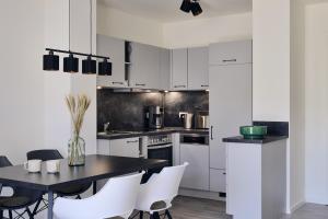 a kitchen with white cabinets and a black table and chairs at Apartment C2 - barrierefrei mit großer Südterrasse und Naturblick im "Pine Hill Resort" in Zirchow