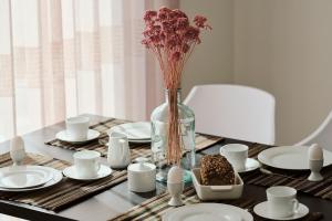 a table with plates and a vase with flowers in it at Apartment C2 - barrierefrei mit großer Südterrasse und Naturblick im "Pine Hill Resort" in Zirchow