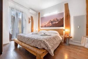 a bedroom with a large bed with a mountain painting on the wall at Le Coccinelle Home in Mandello del Lario