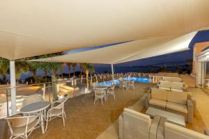 a restaurant with tables and chairs on a balcony at Queens Bay Hotel in Paphos