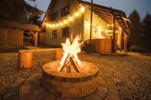 a fire pit in front of a house with lights at Csalóka kulcsosház in Harghita-Băi