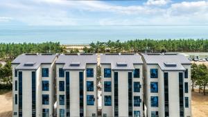 an apartment building with blue windows in front of the ocean at Gangneung Music Time Spa Pension in Gangneung