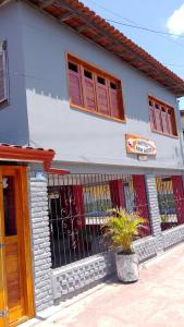 um edifício branco com janelas vermelhas e uma cerca em HOSTEL Bom Gosto em Canavieiras