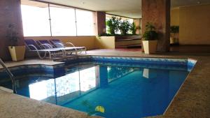 a large swimming pool in a hotel room with chairs at Apart Hotel Leblon Ocean in Rio de Janeiro