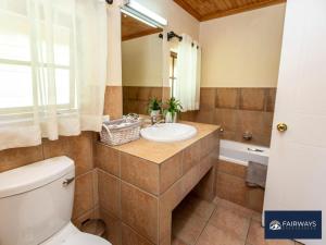 a bathroom with a sink and a toilet and a tub at Fairways Drakensberg Resort in Drakensberg Garden