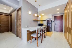 a kitchen with a white counter and chairs in a room at Comfort and Spacious 3BR at Sky House BSD Apartment By Travelio in Tangerang