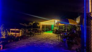 a patio with a table and an umbrella at night at Tourist Land Resort - Rani Cottage in Dharān Bāzār