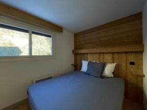 sypialnia z łóżkiem i drewnianą ścianą w obiekcie Homency - Résidence le Sanghri-La w LʼAlpe-dʼHuez