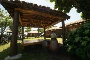 un pabellón de madera con un banco en el césped en Traditional Hanok thatched house, en Seogwipo
