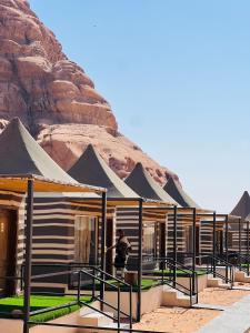a man standing in front of a building in front of a mountain at Eva Desert Camp in Wadi Rum +76 photos