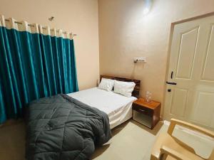 a bedroom with a bed and a blue curtain at GURI Homestay in Kushālnagar