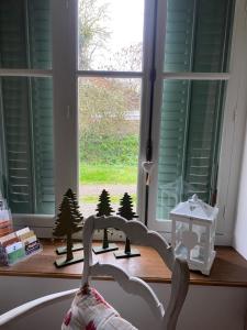 a window with miniature christmas trees and a shelf with a christmas ornament at Petite maison de charme à Thury in Thury