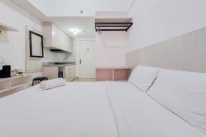 a large white bed in a room with a kitchen at Minimalist Studio at Poris 88 Apartment By Travelio in Tangerang +6 photos