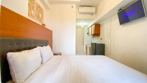 ein Schlafzimmer mit einem großen Bett und weißen Kissen in der Unterkunft Comfortable Studio Room at Tokyo Riverside Apartment By Travelio in Rawalembang