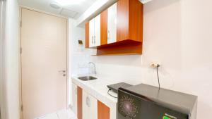 eine kleine Küche mit Spüle und Fernseher in der Unterkunft Comfortable Studio Room at Tokyo Riverside Apartment By Travelio in Rawalembang