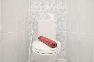 einem rot gerollten Handtuch auf einem WC im Bad in der Unterkunft Comfortable Studio Room at Tokyo Riverside Apartment By Travelio in Rawalembang