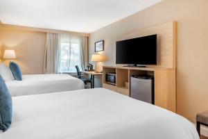 a hotel room with two beds and a flat screen tv at Casco Bay Hotel Portland Airport - Maine Mall, an Ascend Collection Hotel in South Portland