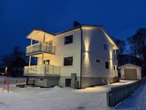 a large white house in the snow at night at Northstay - The Arctic Pearl, Central House with 4 bedrooms and 2 bathrooms in Tromsø