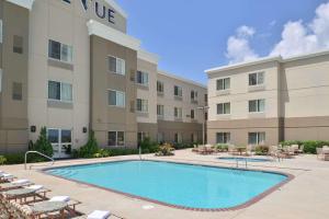 a pool in front of a hotel with chairs at The Hotel Vue in Natchez