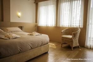 a bedroom with a bed and a chair and window at Hotel Saraceno Resort with Private Beach in Milano Marittima +182 photos