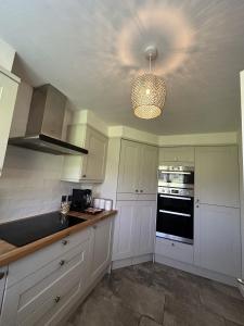 a kitchen with white cabinets and a ceiling at Cosy Corby Getaway in Corby +11 photos