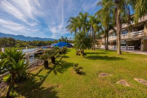 a park with palm trees and a blue umbrella at Lindo Loft na Praia de Barra do Una à beira do Rio in São Sebastião