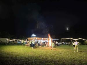 a group of people standing around a fire in a field at NaNa Farm in Bak Kan