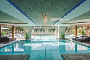 a large swimming pool with blue tile floors and windows at Hotel Weiher Green Lake in Falzes