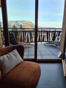 ein Zimmer mit einem Stuhl und einem Balkon mit Aussicht in der Unterkunft La Feclaz - Duplex 90m2 au pied des pistes in Les Déserts