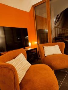 ein Wohnzimmer mit 2 orangenen Stühlen und einem Tisch in der Unterkunft La Feclaz - Duplex 90m2 au pied des pistes in Les Déserts + 31 Fotos